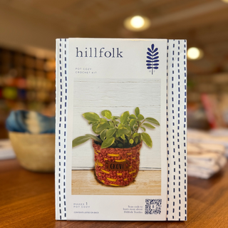 Hillfolk crochet kit packaging on a wooden surface with a blurred indoor background